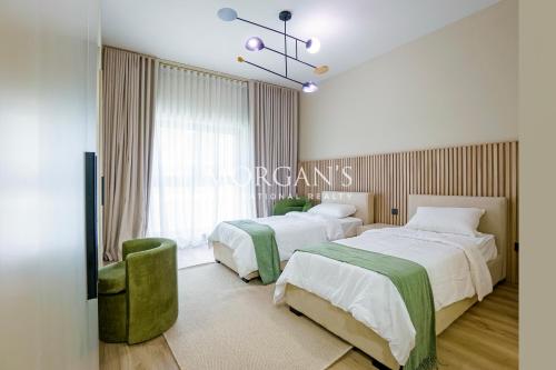 a bedroom with two beds and a green chair at Stunning Brand New 2 BR in Fairmont in Dubai