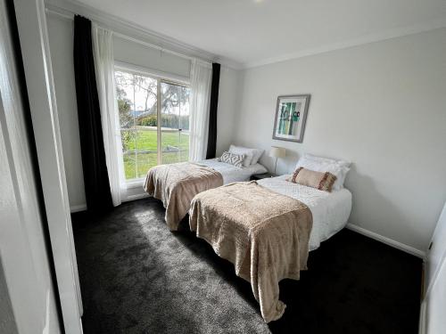 two beds in a room with a window at Winterwood Lodge - 6mins Jindabyne Pets Allow Farm Stay-Swimming Pool Summer Only in Moonbah