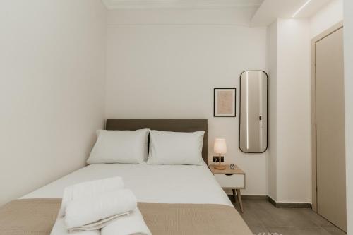 Habitación blanca con cama y espejo en Urban Elegance in Thessaloniki, en Tesalónica