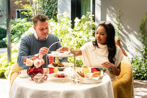a man and a woman sitting at a table eating food at Cabosse, Boutique Palace & Spa in Antwerp
