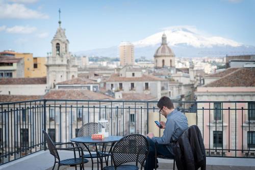 a man sitting at a table looking at his cell phone at Ostello degli Elefanti in Catania