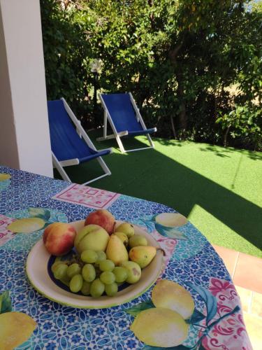 a plate of fruit on a table with two chairs at Sul mare con spiaggetta privata vicino a Cefalù. in Buonfornello