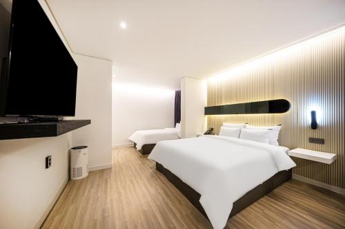 a bedroom with a large white bed and a flat screen tv at Browndot Hotel Gwangju Pungam in Gwangju
