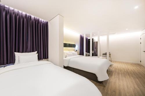 2 camas en una habitación de hotel con cortinas moradas en Browndot Hotel Gwangju Pungam, en Gwangju