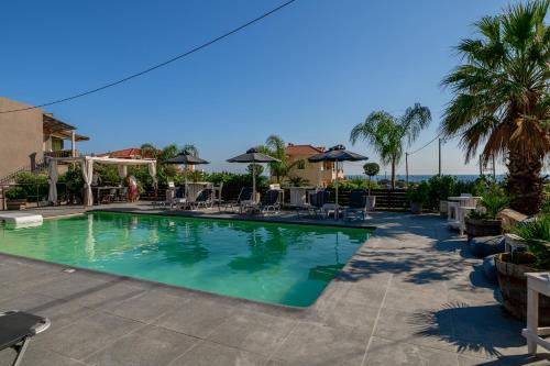 a large swimming pool with chairs and umbrellas at Evita Studios in Svoronata