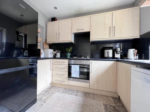 a kitchen with wooden cabinets and appliances at Beautiful Private Room in Levenshulme in Manchester