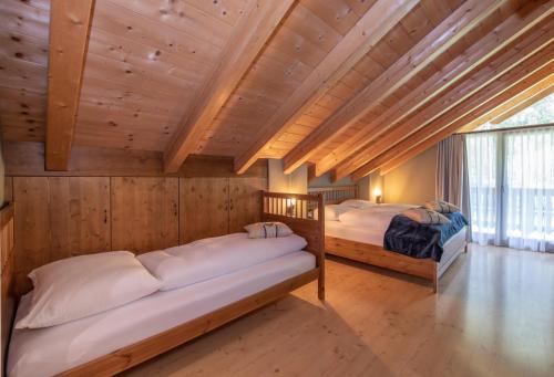 two beds in a room with wooden walls at Enzianhütte in San Giuseppe in Anterselva