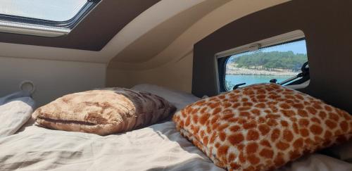 a camper with a bed with a giraffe pillows on it at Camper Relax in Murter Slanica beach - with clima in Tisno