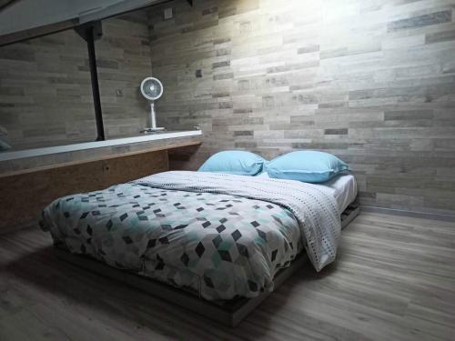 1 dormitorio con 1 cama con almohadas azules y pared de ladrillo en Villadali-fr Appart Hôtel TOULON Clim, Wifi, Terrasse, Cuisine Parking Gratuit, en Toulon