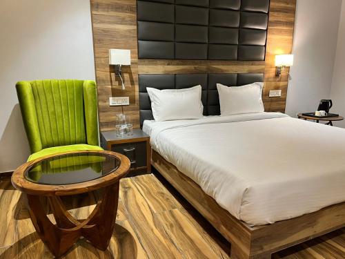a bedroom with a bed and a green chair at Hotel Tamarind Tree in Kharar