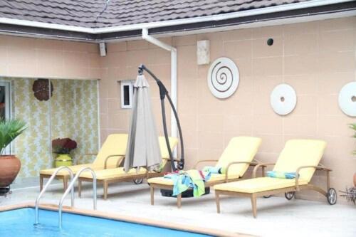 un grupo de sillas y una sombrilla junto a una piscina en Palazzo Dumont Hotel, en Ikuata