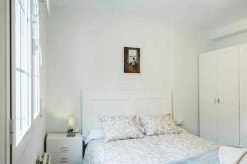 a white bedroom with a bed and a picture on the wall at Apartamento Centro Granada in Granada