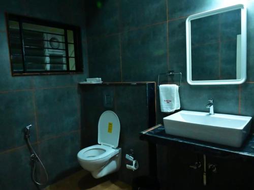 a bathroom with a white toilet and a sink at Sunshine International Boarding & Lodging in Belūr