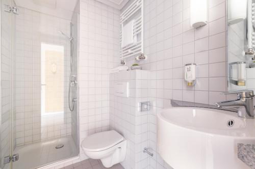 a white bathroom with a toilet and a sink at Novum Akademiehotel Kiel in Kiel