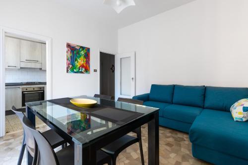 ein Wohnzimmer mit einem Tisch und einem blauen Sofa in der Unterkunft Appartamento Ibisco by Wonderful Italy in Bologna
