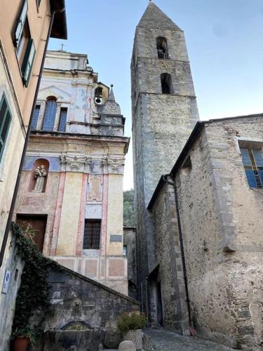 an old building with a clock tower next to another building at Iconic Italian Townhouse w Rooftop Terrace & Mountain View, Pigna in Pigna