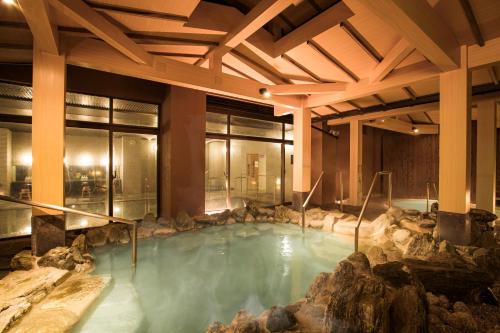 uma grande piscina de água com pedras num edifício em Toba International Hotel Shiojitei em Toba