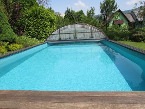 a swimming pool with a greenhouse on top of it at Dům u rybníka in Nýdek