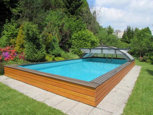 a large swimming pool in a garden with a deck at Dům u rybníka in Nýdek