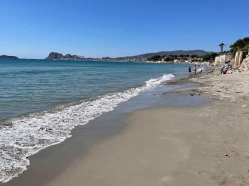 une plage avec des gens debout sur le sable et l'eau dans l'établissement Cocon les pieds dans l'eau Accès direct à la mer, à La Ciotat