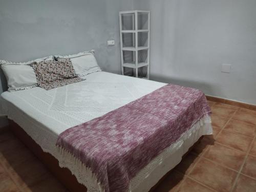 a bedroom with a bed with a purple blanket on it at casa señorial Sara in Trigueros