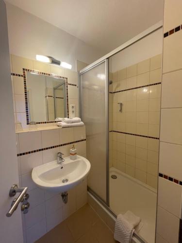 a bathroom with a sink and a shower at Hotel Restaurant Steinhägerquelle in Steinhagen