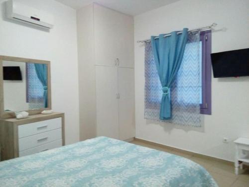 a bedroom with a bed and a window with blue curtains at Vourkari Studio 2 with kitchen in Ioulis