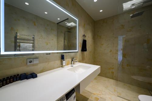 łazienka z umywalką i dużym lustrem w obiekcie Roze Kūrmājas Residence w mieście Lipawa