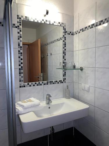 a white bathroom with a sink and a mirror at Hotel Restaurant Steinhägerquelle in Steinhagen