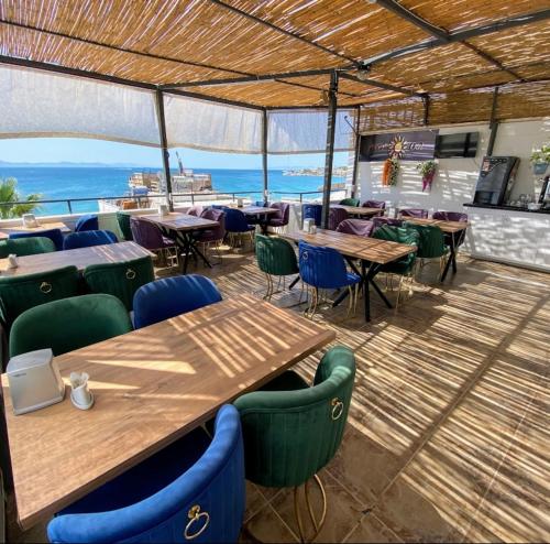 ein Restaurant mit Tischen und Stühlen und Blick auf das Meer in der Unterkunft Acer Güneş Otel in Didim
