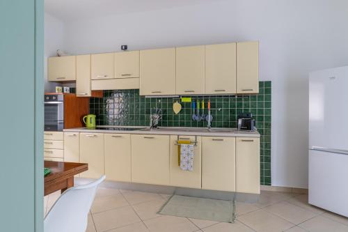 una cocina con armarios blancos y una pared de azulejos verdes en Maranto Terra - YourPlace Abruzzo, en Fossacesia