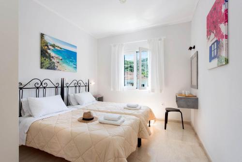 a white bedroom with two beds and a table at Balaris Apartments in Kassiopi