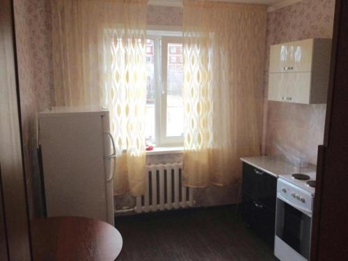 eine kleine Küche mit einem Fenster und einem Kühlschrank in der Unterkunft ЛЮКС на Юго-востоке,Степной1 in Qaraghandy