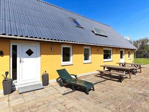 a yellow house with a bench and a picnic table at 10 person holiday home in Vinderup in Vinderup