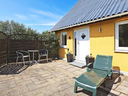 a patio with a table and chairs and a yellow house at 10 person holiday home in Vinderup in Vinderup