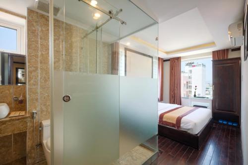 uma casa de banho com uma cabina de duche em vidro e uma cama em Minh Tuyết Luxury Hotel managed by HT em Nha Trang