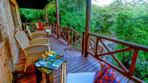 a wooden porch with chairs and a table with a book at Mara Leisure Camp in Talek