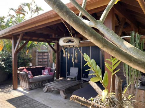 a pergola with a couch and a chair on a patio at L'Orée du Maïdo in Le Guillaume