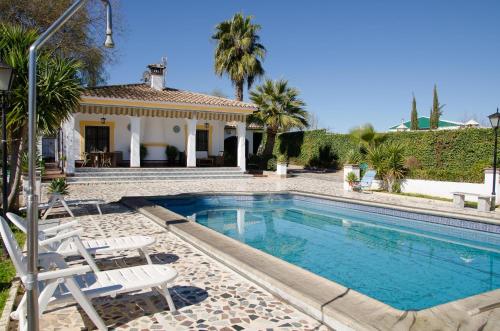 a swimming pool with two chairs and a house at Villa Vacacional Los Naranjos in Montemayor