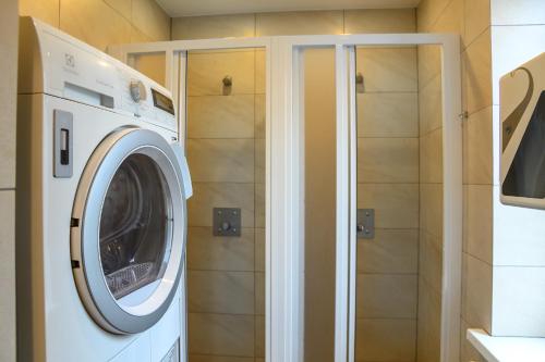 a washing machine in a bathroom with a shower at Klaipeda Hostel in Klaipėda