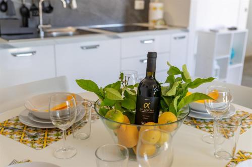 a bottle of wine and glasses on a table with lemons at Verde Oliva Residence in Ispica