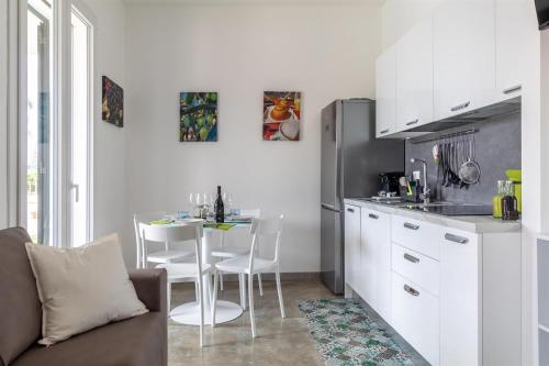 a kitchen with a table and a kitchen with white cabinets at Verde Oliva Residence in Ispica