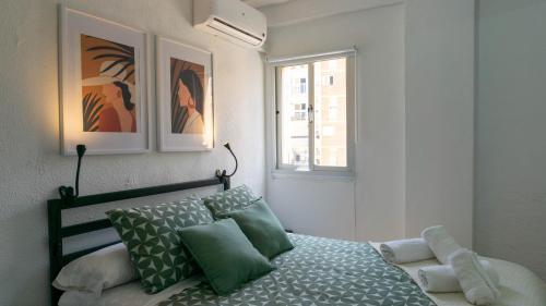 une chambre avec un lit avec des oreillers verts et une fenêtre dans l'établissement Home Corinto Beach terraza y piscina - Benalmadena Malaga, à Benalmádena