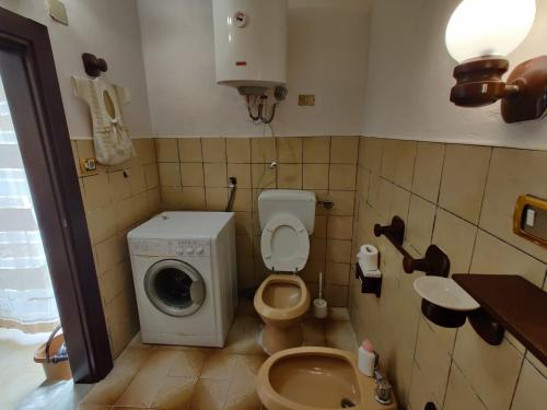 een kleine badkamer met een wasmachine en een toilet bij Domus Aurea da Carlo in Ravanusa