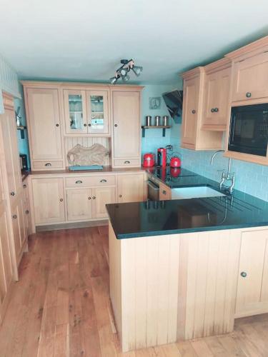 a kitchen with wooden cabinets and a black counter top at Crossways Cottage & hot tub - Symonds Yat in Symonds Yat