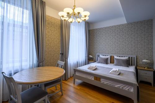 a bedroom with a bed and a table and a chandelier at Roze Kūrmājas Residence in Liepāja