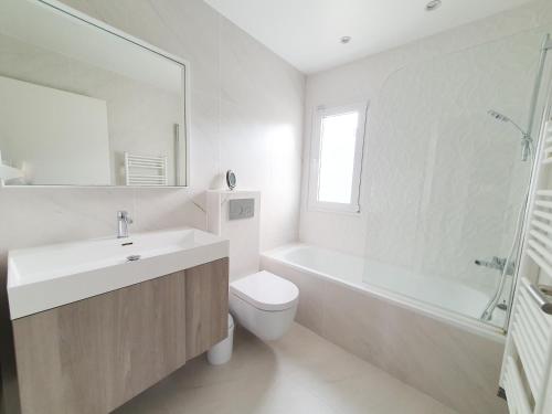 a bathroom with a sink and a toilet and a tub at EXIGEHOME- Maison d'architecte avec SPA - V2 in Orgeval
