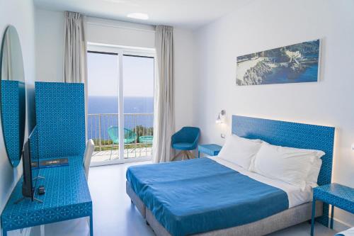 1 dormitorio con cama azul y balcón en Hotel Orsa Maggiore, en Castro di Lecce