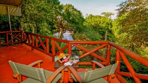 a table and chairs on a bridge with a river at Mara Leisure Camp in Talek