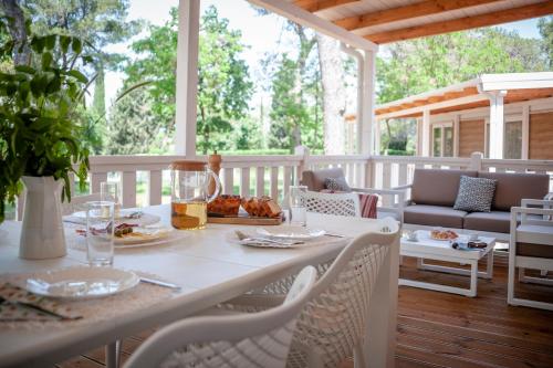 a table and chairs on a porch with food on it at Glamping and Mobile Homes Lavanda - Holiday Centre Bi VIllage in Fažana